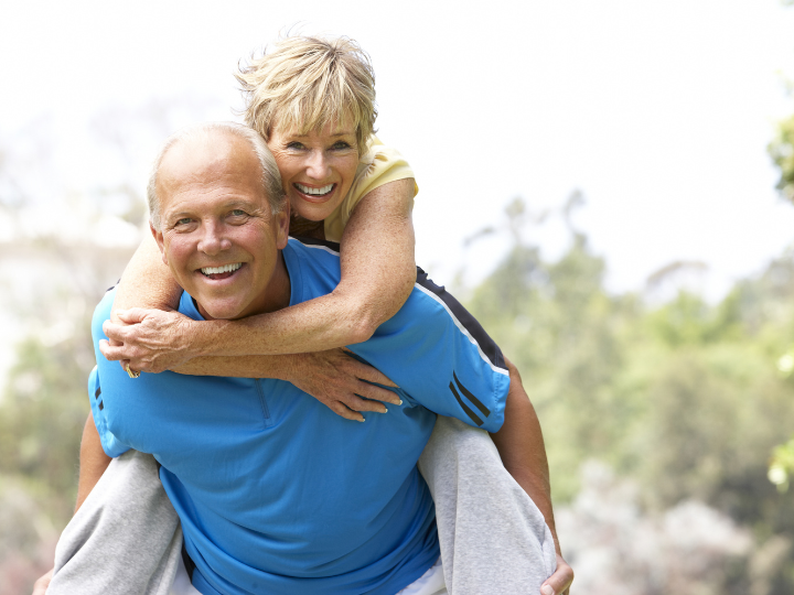 Elderly couple walking with woman piggybacking