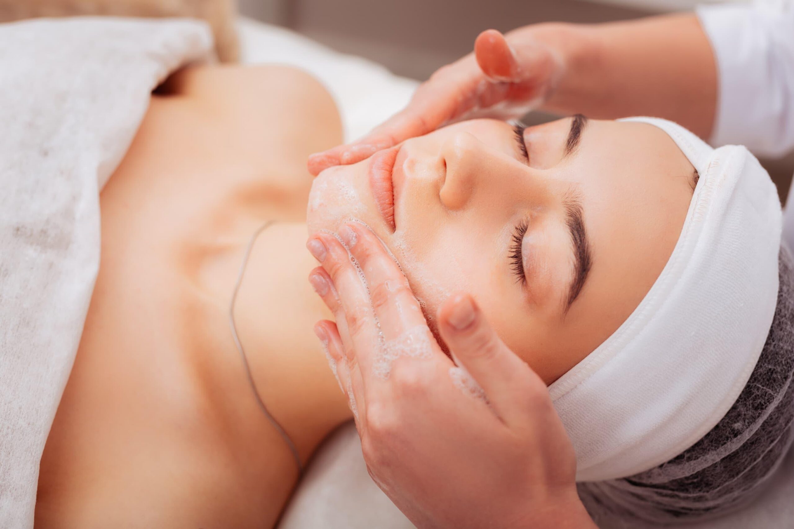 A woman getting a brightening facial form a professional in a relaxing medical spa environment for a luminous glow.