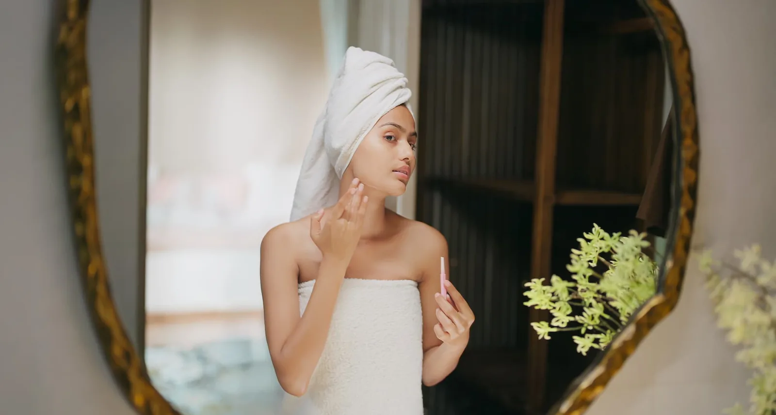 A woman inspecting her face in the mirror, camera-ready during the return-to-public phase of CO2 laser recovery at Coastal Health & Medical Spa
