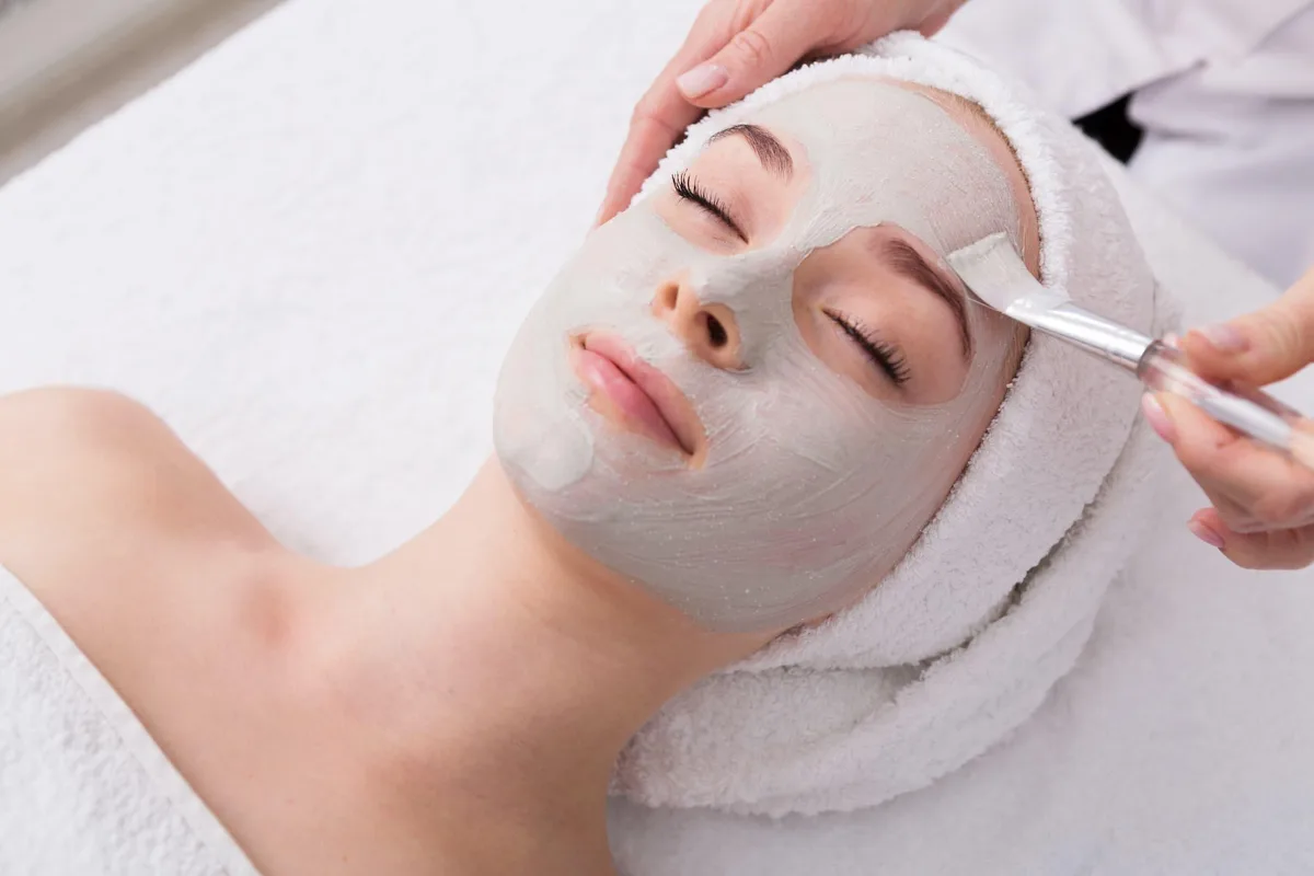 A woman receiving a bridal facial with a treatment mask at a med spa, the kind of professional facial brides schedule monthly before a wedding.