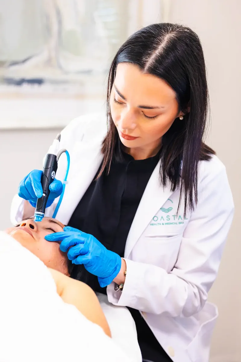 A Coastal Health & Medical Spa provider using a HydraFacial handpiece during a facial treatment in Jacksonville, FL