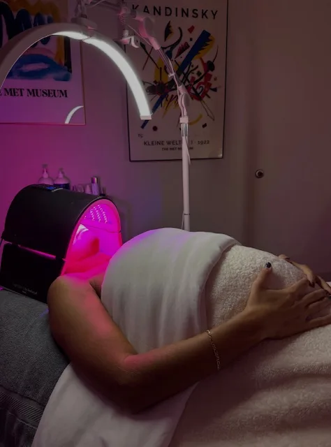 A client under the red LED light therapy panel after a facial at Coastal Health & Medical Spa in Jacksonville, FL, an enhancement that can be added to a brightening facial.