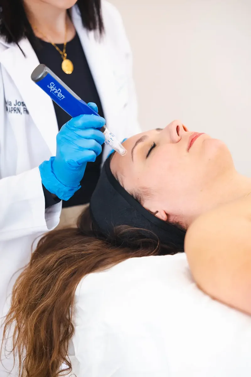 Close-up of the SkinPen microneedling device in Dr. Olivia's gloved hand as it glides across a patient's cheek at Coastal Health & Medical Spa in Jacksonville, FL.