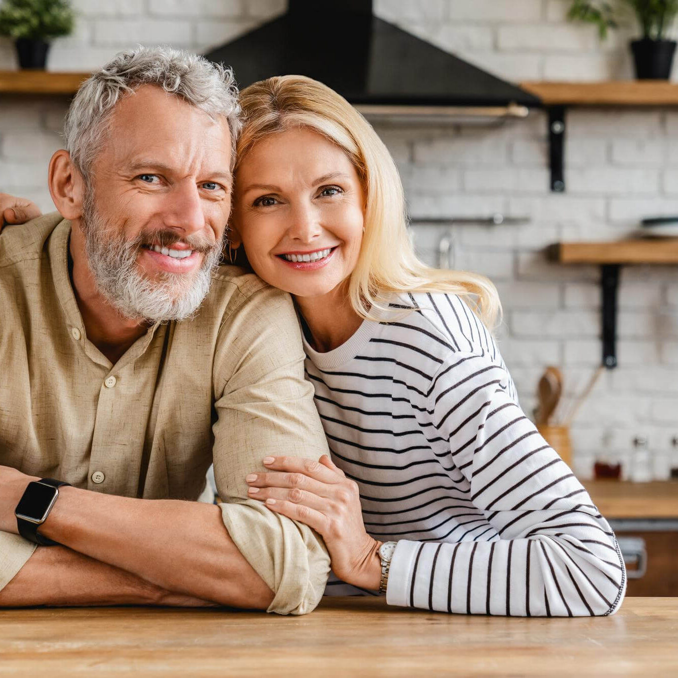 portrait-middle-aged-couple-hugging-while-standing-together-kitchen-home (1)